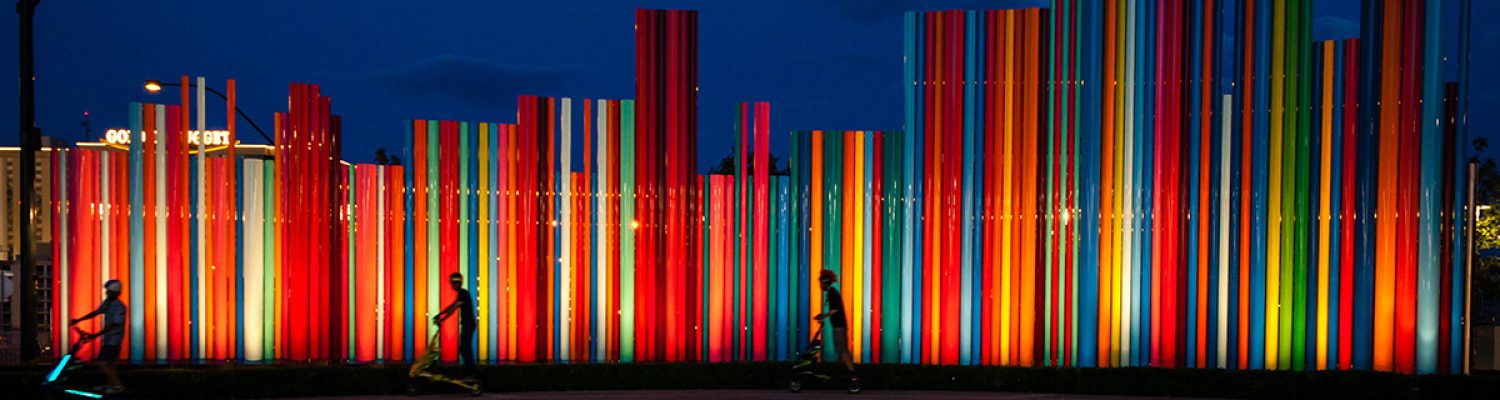 colorful fence with people on scooters in front of it